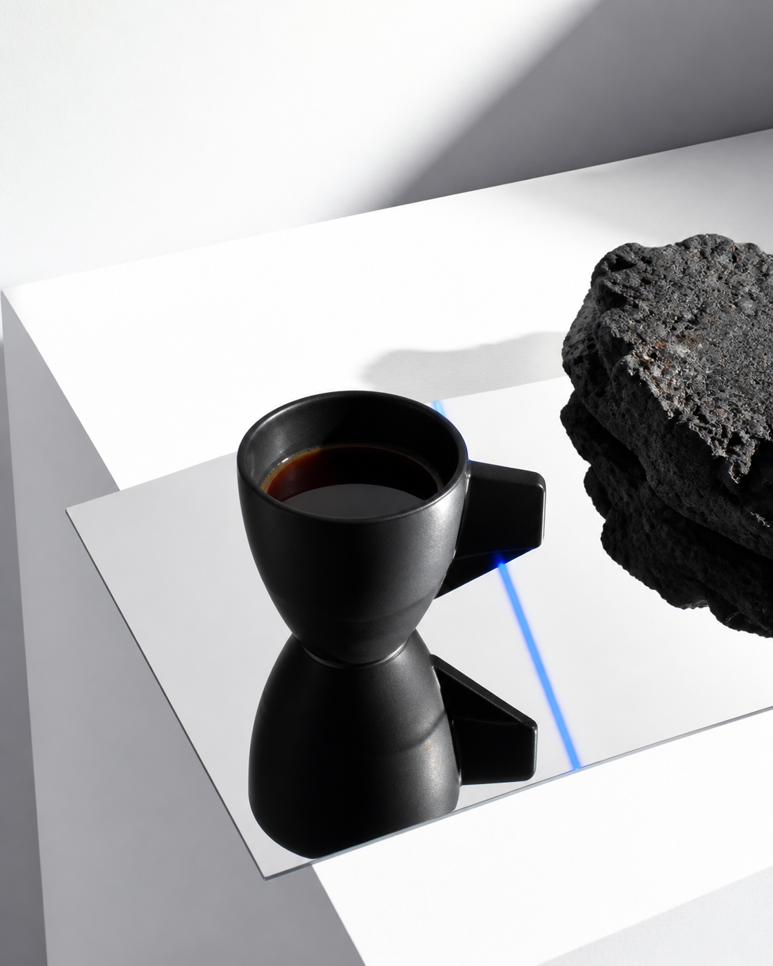 白い空間に置かれた黒いカップとコーヒーのモードなビジュアル